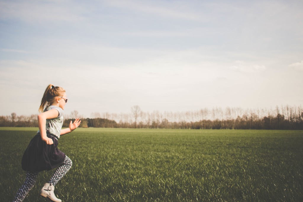 A girl runs across a green field.